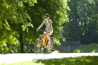 Deutschland, Bayern, München, Frau fährt mit dem Mountainbike durch den Park - DSF00099