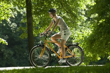 Germany, Bavaria, Munich, Woman mountain biking across park - DSF00098