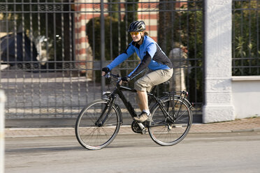 Italy, Trento, Torbole, Female mountainbiker riding across street - DSF00085