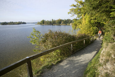 Germany, Bavaria, Staffelsee, Person mountain biking alongside lake - DSF00080