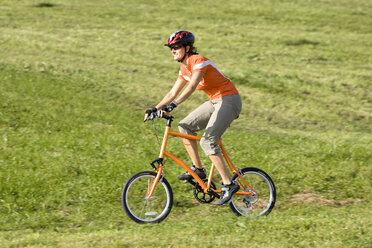 Deutschland, Bayern, Oberland, Frau fährt mit dem Mountainbike über ein Feld - DSF00079