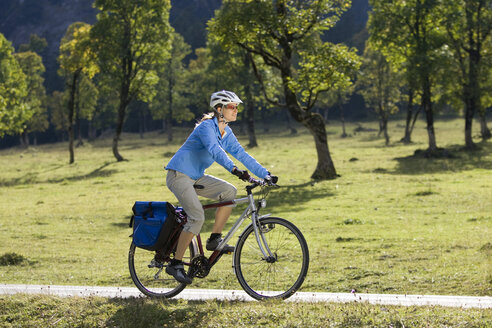 Österreich, Tirol, Ahornboden, Frau beim Mountainbiken, Bäume im Hintergrund - DSF00064