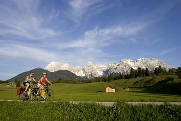 Deutschland, Bayern, Mittenwald, Zwei Frauen fahren mit dem Mountainbike über die Landstraße - DSF00047