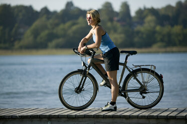 Germany, Bavaria, Tegernsee, Woman with mountain bike on landing stage - DSF00017