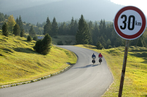 Deutschland, Bayern, Mittenwald, Pärchen beim Mountainbiking, Verkehrsschild im Vordergrund - DSF00011