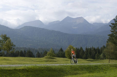 Deutschland, Bayern, Mittenwald, Frau beim Mountainbiken vor Bergkulisse, lizenzfreies Stockfoto