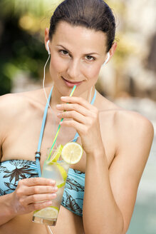 Junge Frau im Bikini hält ein Zitronengetränk - ABF00435