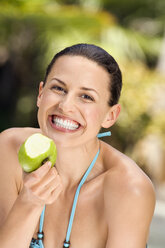 Young woman in bikini holding apple, smiling, close-up - ABF00434