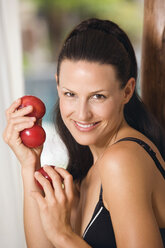 Young woman wearing neglige, holding plums, portrait, close-up - ABF00419