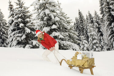 Österreich, Salzburger Land, Altenmarkt, Junge Frau zieht einen mit Weihnachtspaketen beladenen Schlitten - HHF02610