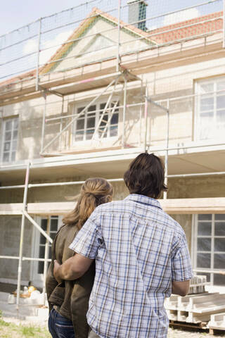 Ehepaar beim Betrachten eines neuen Hauses, Rückansicht, lizenzfreies Stockfoto