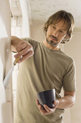 Young man using a putty knife, portrait - WESTF09058