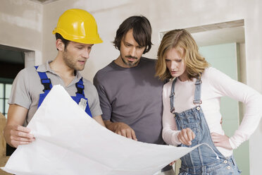 Junges Paar und Bauarbeiter betrachten einen Bauplan - WESTF09031