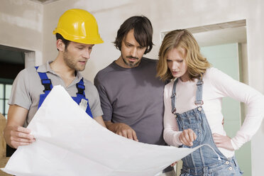 Young couple and construction worker looking at construction plan - WESTF09031