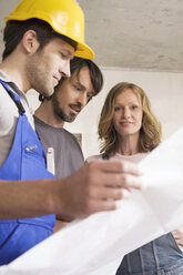 Young couple and construction worker looking at construction plan - WESTF09030