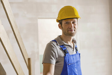 Construction worker at construction site, smiling, portrait - WESTF09002