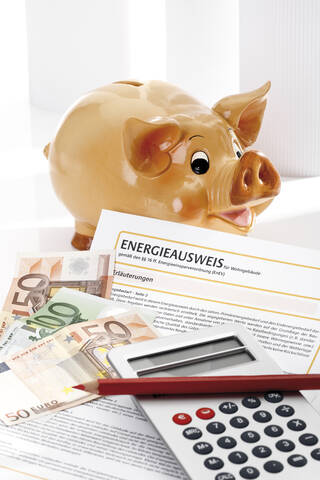 Sparschwein, Energieausweis, Taschenrechner und Euro-Scheine, Nahaufnahme, lizenzfreies Stockfoto