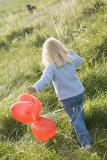 Little girl (3-4) walking with balloons in the meadow, rear view - SMOF00181