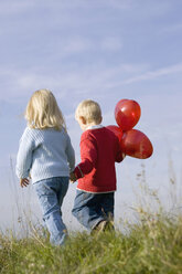 Little girl and boy (3-4) walking hand in hand, rear view - SMOF00175