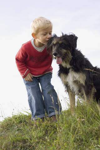 Kleiner Junge (3-4) spielt mit Hund, lizenzfreies Stockfoto