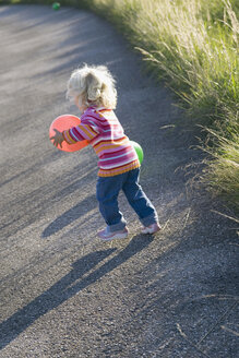 Little girl (2-3) playing with balloons outdoors, rear view - SMOF00159