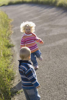 Little girl (2-3) and boy (1-2) playing on path - SMOF00151