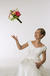 Junge Braut wirft Brautstrauß, lachend - NHF00918