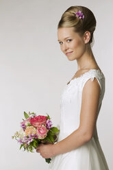 Young bride holding bridal bouquet, side view - NHF00888