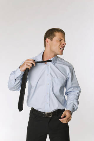Geschäftsmann, der seine Krawatte lockert und wütend aussieht, lizenzfreies Stockfoto