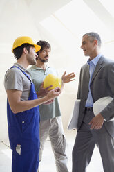 Two men talking to Architect at construction site - WESTF08998