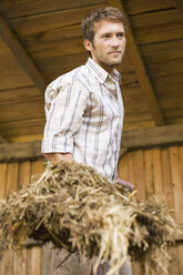 Farmer shovelling hay in barn - BMF00443