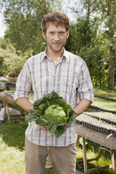 Man holding savoy cabbage, portrait - BMF00423