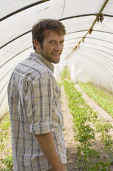 Man in greenhouse, smiling, portrait - BMF00422