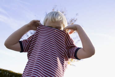 Kleiner Junge (4-5) trägt ein gestreiftes Hemd, flacher Blickwinkel - SMO00259