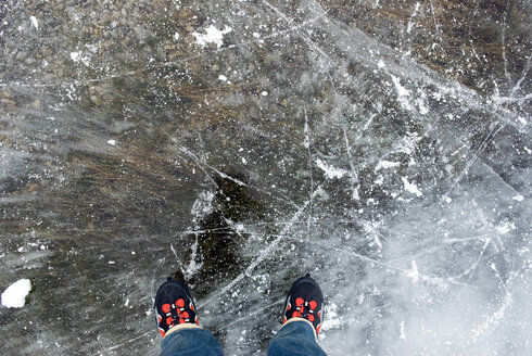 Person mit Schlittschuhen auf zugefrorenem See stehend, Blick von oben - AWDF00288