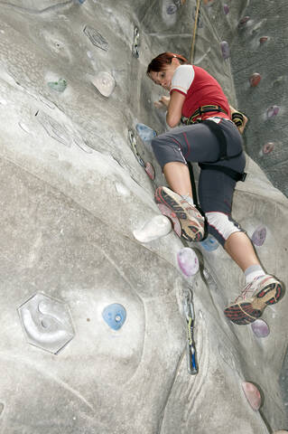 Young woman on indoor climbing wall, low angle view stock photo