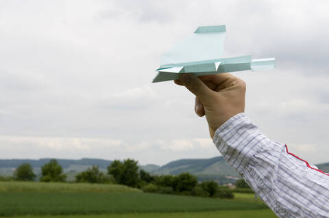 Hand hält Papierflugzeug, Nahaufnahme, lizenzfreies Stockfoto