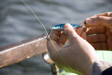 Man's hand fixing bait on hook, elevated view - AWDF00160