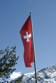 Schweiz, Arosa, Schweizer Fahne am Fahnenmast unter blauem Himmel - AWDF00098