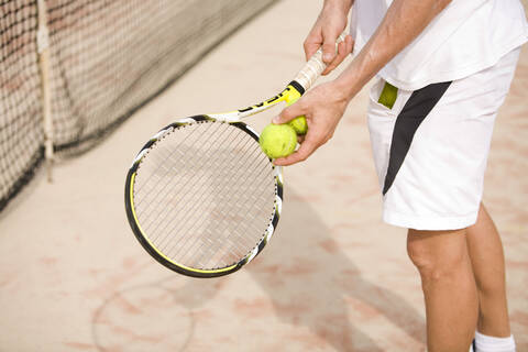 Male tennis player holding tennis racket, low section stock photo