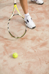 Man holding tennis racket, ball on ground - UKF00164