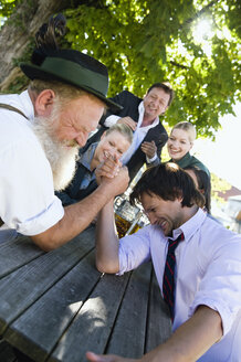 Germany, Bavaria, Upper Bavaria, Two men in beer garden arm wrestling - WESTF09740