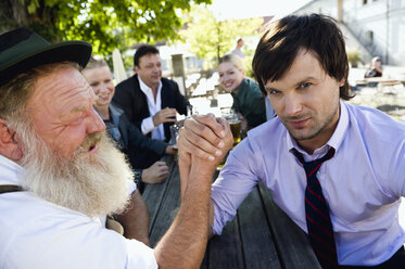 Deutschland, Bayern, Oberbayern, Zwei Männer im Biergarten beim Armdrücken - WESTF09736