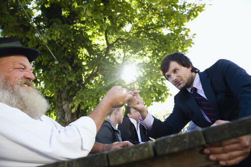 Germany, Bavaria, Upper Bavaria, Two men in beer garden finger wrestling - WESTF09733