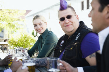 Deutschland, Bayern, Oberbayern, Geschäftsleute und Punk im Biergarten, lächelnd - WESTF09718