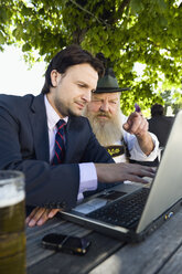 Deutschland, Bayern, Oberbayern, älterer bayerischer Mann und junger Geschäftsmann mit Laptop im Biergarten - WESTF09701