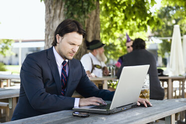 Deutschland, Bayern, Oberbayern, Junger Geschäftsmann im Biergarten mit Laptop - WESTF09691