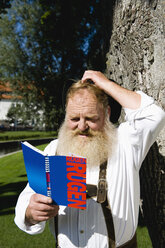 Germany, Bavaria, Upper Bavaria, Bavarian man reading travel book, close-up - WESTF09688