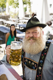 Germany, Bavaria, Upper Bavaria, Senior man in beer garden holding beer stein, portrait - WESTF09608