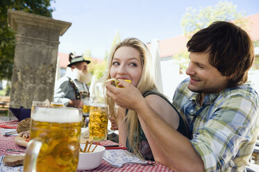 Germany, Bavaria, Upper Bavaria, Young man feeding woman in beer garden - WESTF09605